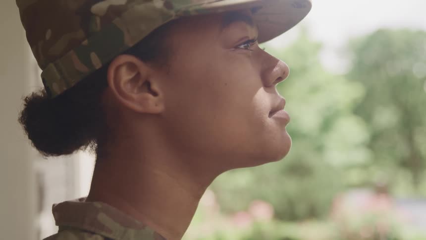 Woman wearing military fatigues looks up