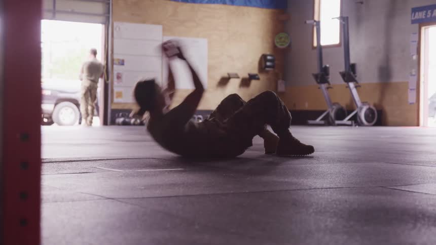 A fenake american soldier working out on the ground inside a gym