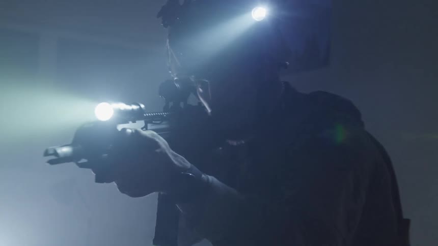 A soldier with his rifle raised turns and looks in to the distance