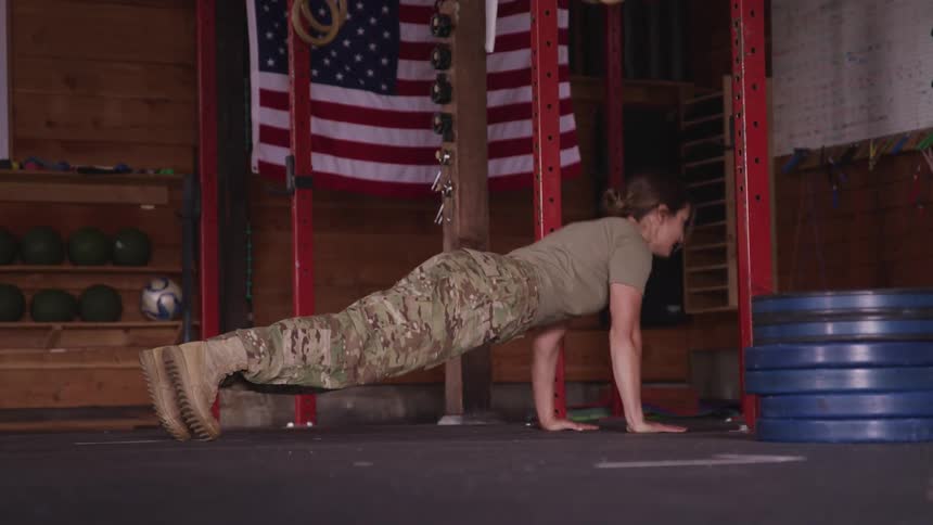 A female soldier does push ups indoors