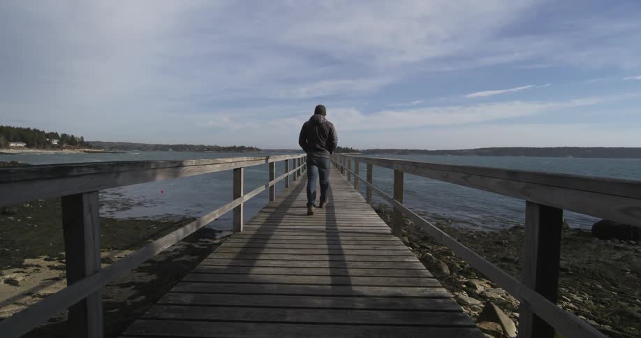A man walking down a pier on a cold day