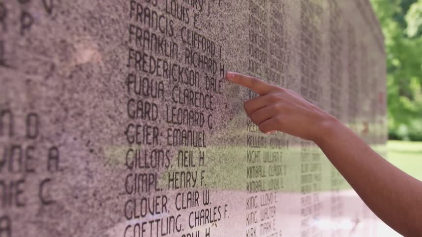 A person touching a memorial wall