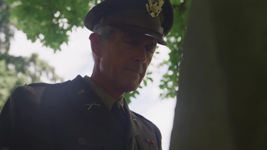 A veteran looks down at a gravestone