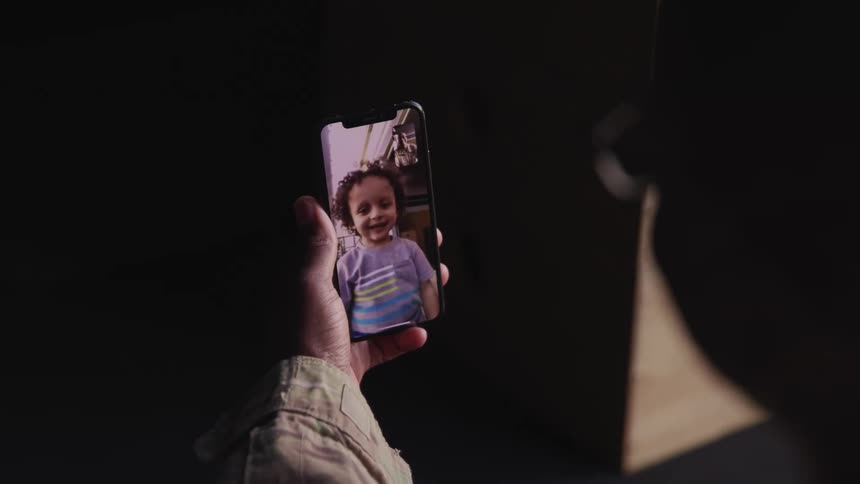 A person in a room with glasses video chatting on a smart phone with a wall in the background
