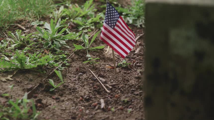 A small american flag stuck in dirt on the ground