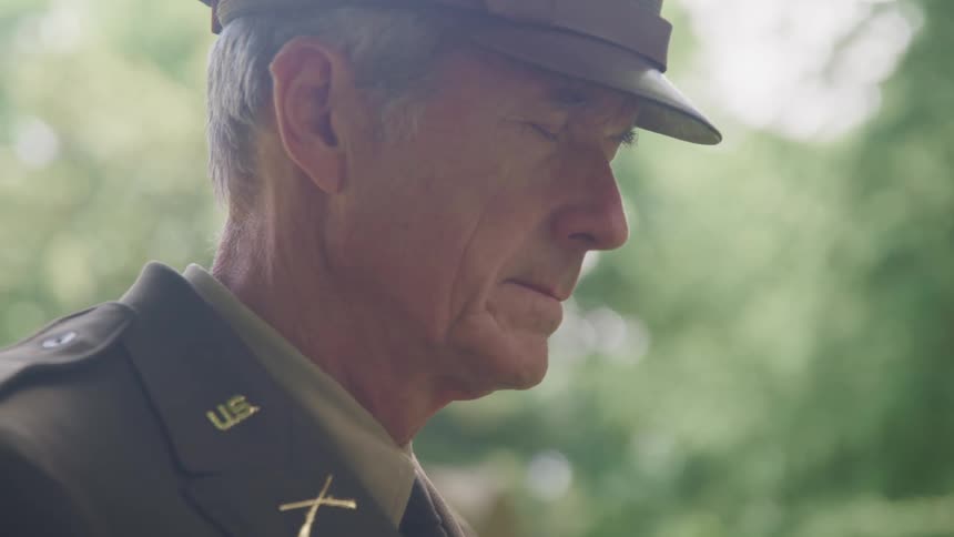 A soldier is standing outside with his eyes closed