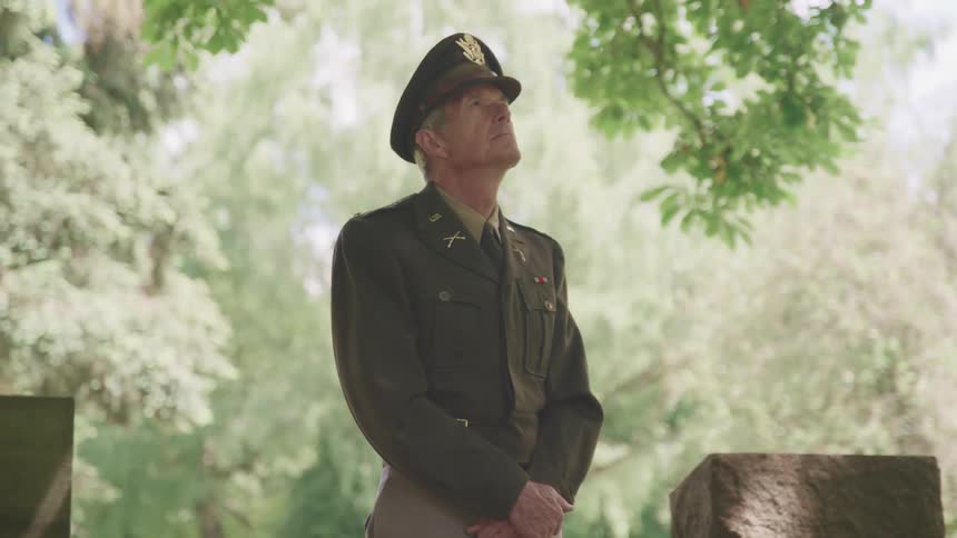 A servicemember in uniform standing next to a grave in a cemetery