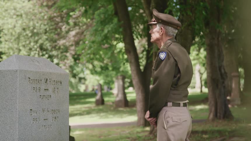 A soldier standing at a tomb in a cemetery