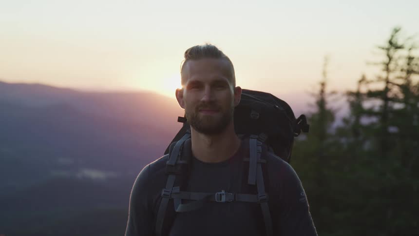 A man is hiking through a forest at dusk