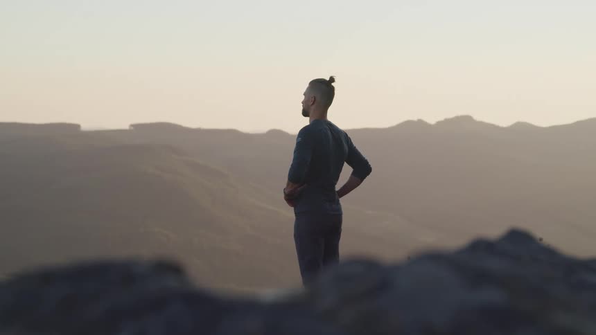 A man stands looking out over a ridge