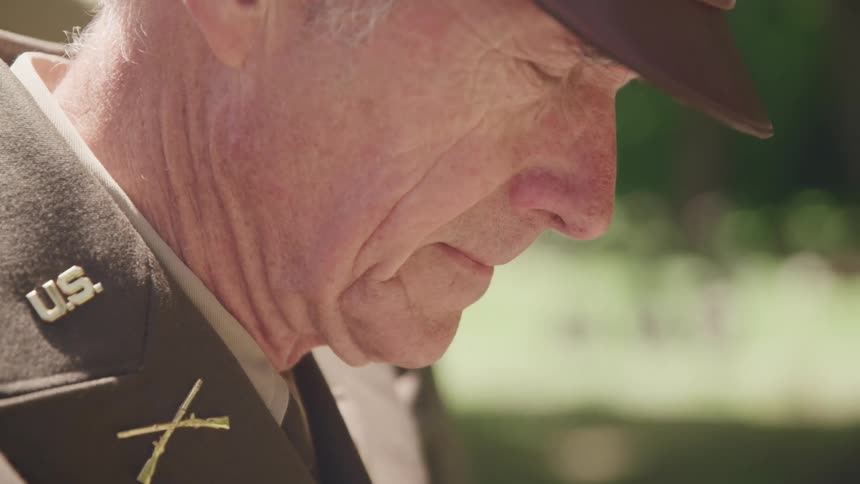 A man in a military uniform outside with trees in the background