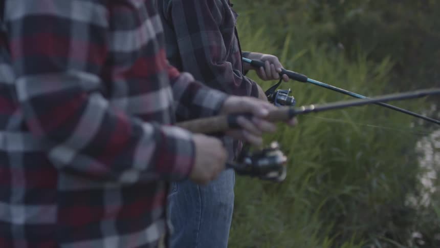 Father and son fishing on a small river at evening
