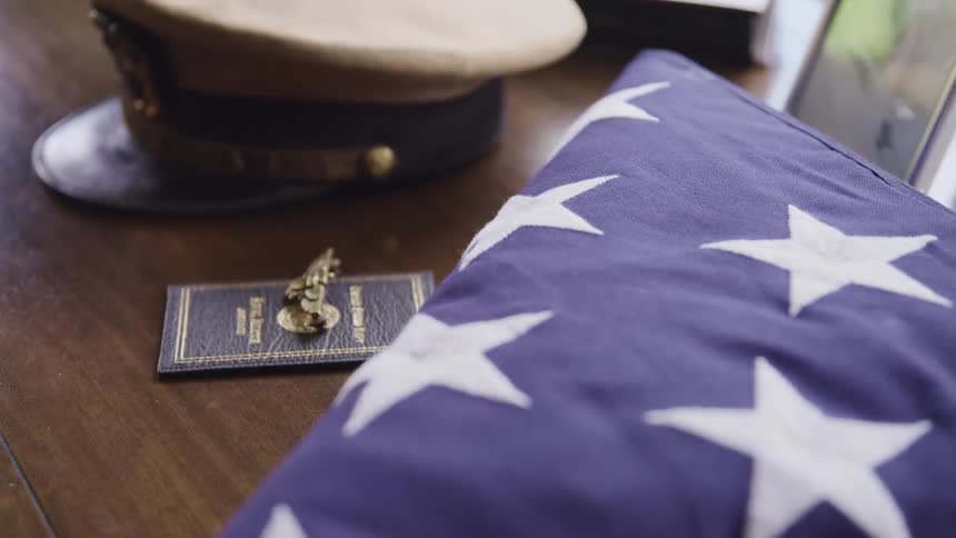 Military objects placed on top of a dresser next to a folder american flag indoors