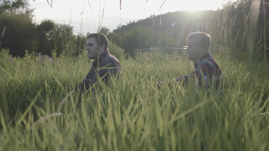 Two men walk through the very tall grass