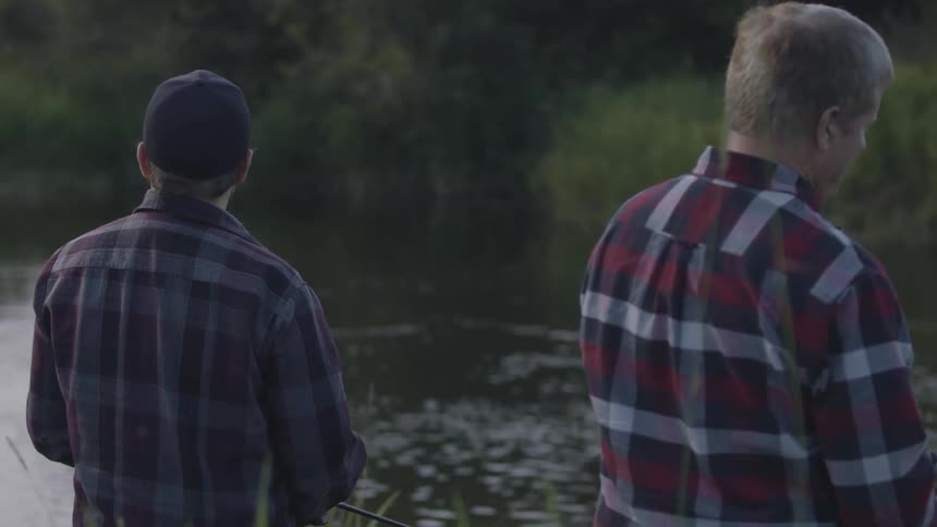 Two men in flannel shirts are fishing in a river