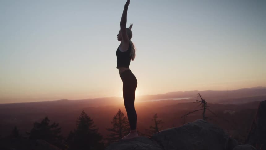 A woman is doing yoga on the mountain top