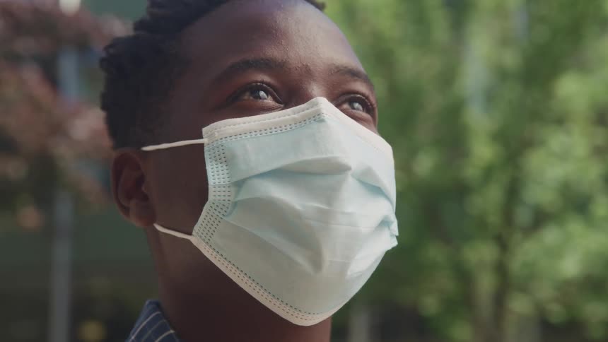 A man is standing outside with a face mask on