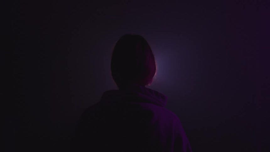 A person stands outside and looks up at the night sky