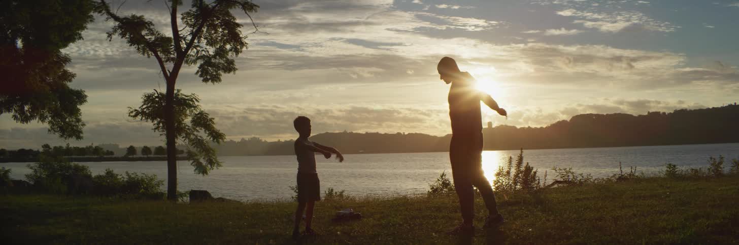 A father and son silhouetted by the sun while stretching and exercising outdoors