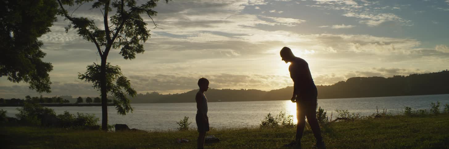 A man and child stretch by the lake at sunrise