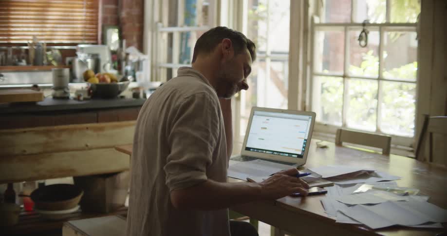 A man uses a calculator and laptop as he goes over paper billing
