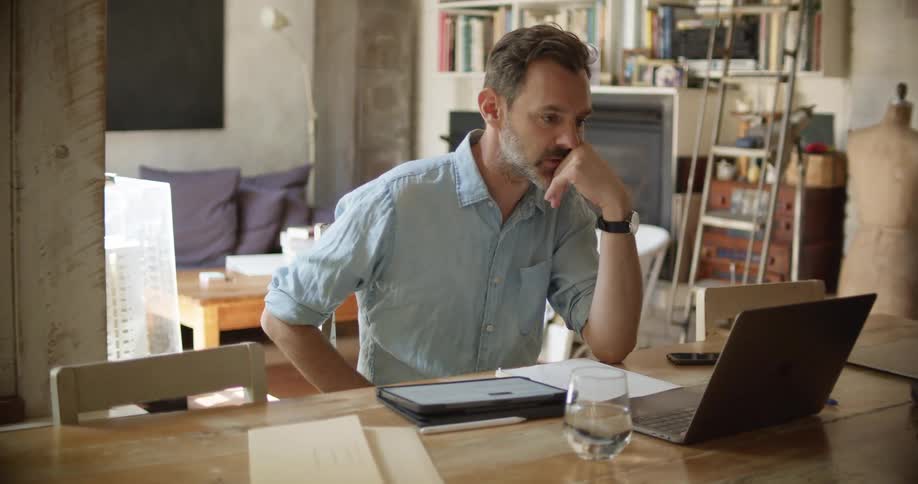 A man is talking on the computer and writing