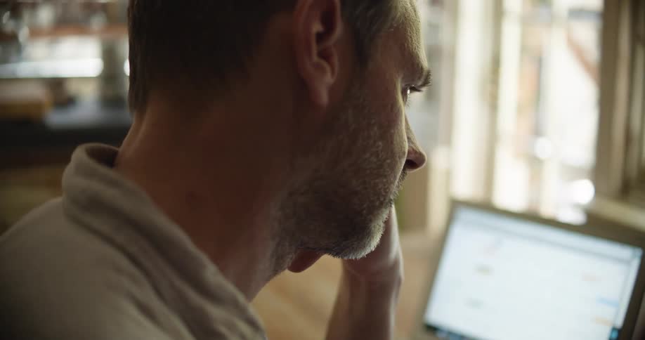 A man is sitting at the table with a laptop opened