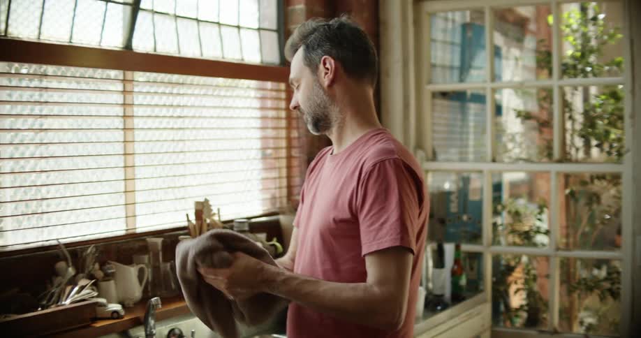 A man washes his hands at his kitchen sink