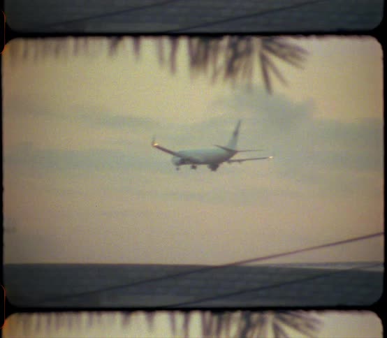 An airplane with lights blinking flies low over neighborhood homes