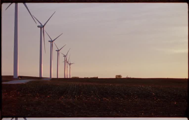 Wind turbines blowing in the wind on a wind turbine farm with the sky and clouds in the background