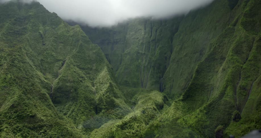 Green covered mountains stand against a cloudy sky