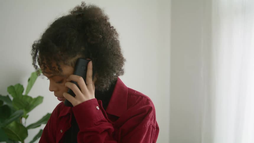 Young woman talking on her smartphone in a room at home