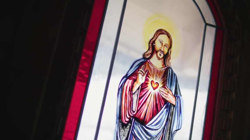 A large stained glass image of jesus fills a church window