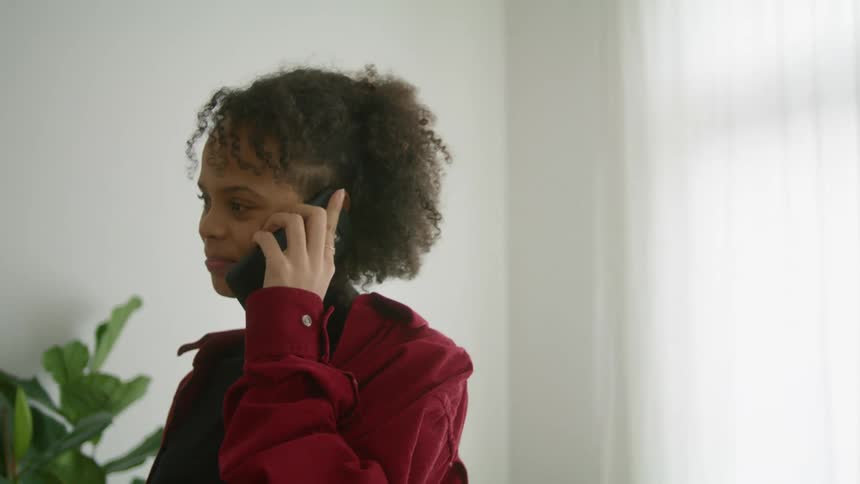 Woman smiling on a call on her smartphone in a room at home