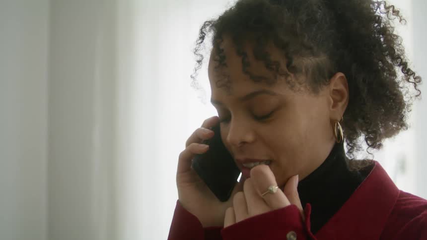 A woman laughs while speaking on her smartphone in a house during the day
