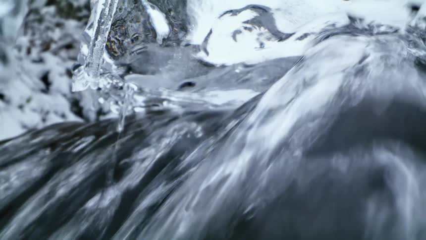 Water pours from underneath a sheet of of ice melting outdoors