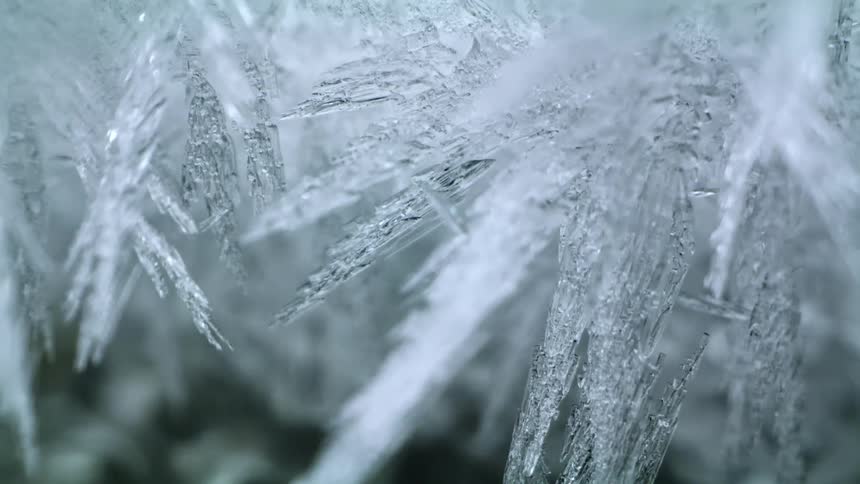 Close up of ice spikes forming over running water on a river at winter
