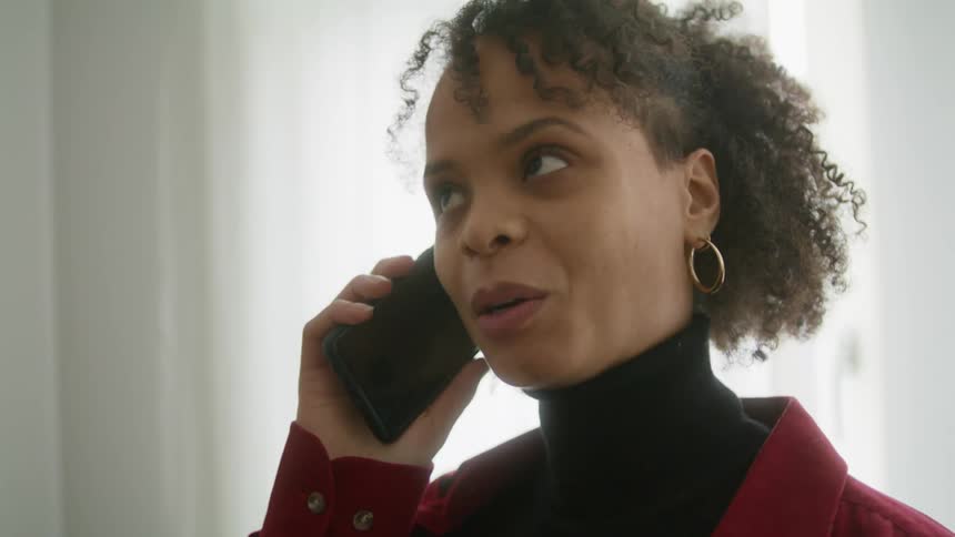 A woman gets excited when her cell phone rings and takes a deep breath and answers it and smiles