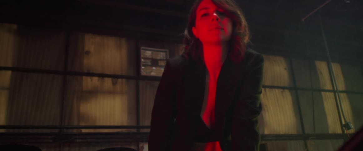 A model poses in a bra and black blazer near a classic car