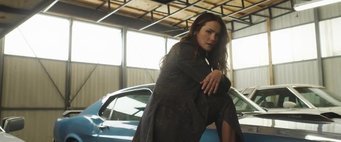A woman is posing on a car
