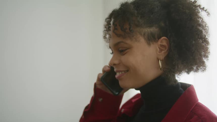 A woman is standing in a room and talking on a cellphone
