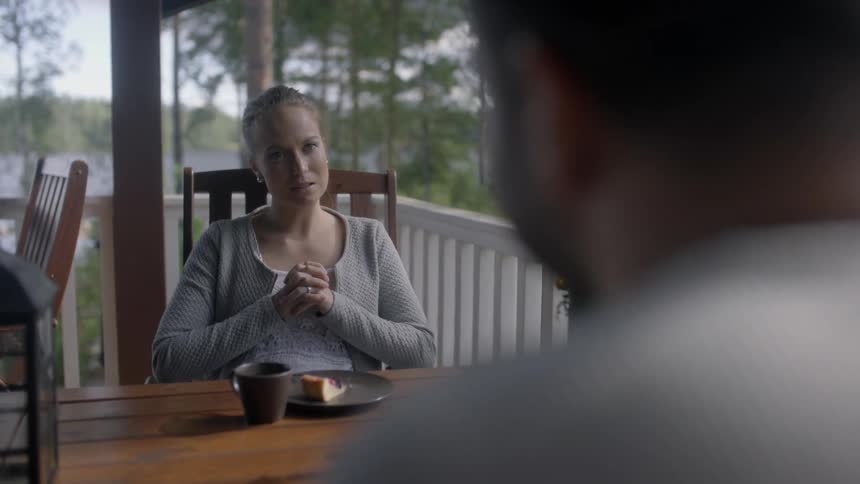 A man and women are talking as they sit on a porch