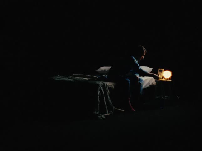 A man sits up from bed and scrolls through his smartphone
