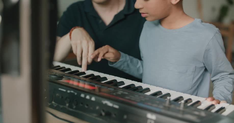 Father instructs son in playing keyboard at home