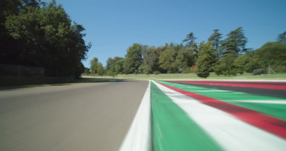 A racetrack next to a fence and trees with the sky and clouds in the background