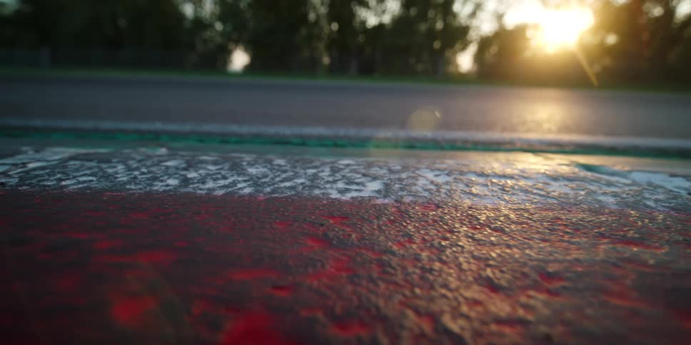 The shoulder of a road is lined with trees on one side and painted in red and white paint on the other