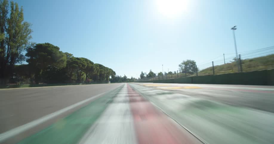 A racetrack next to a fence and trees with the sky and clouds in the background