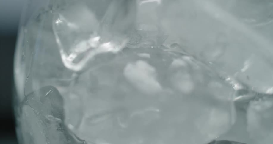 Clear crystal water pouring over ice cubes inside a glass or goblet