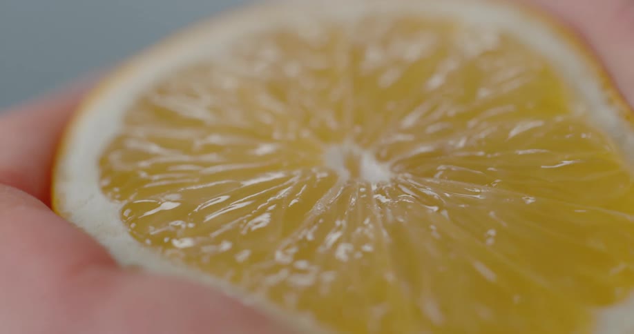 A hand squeezing a juicy lemon