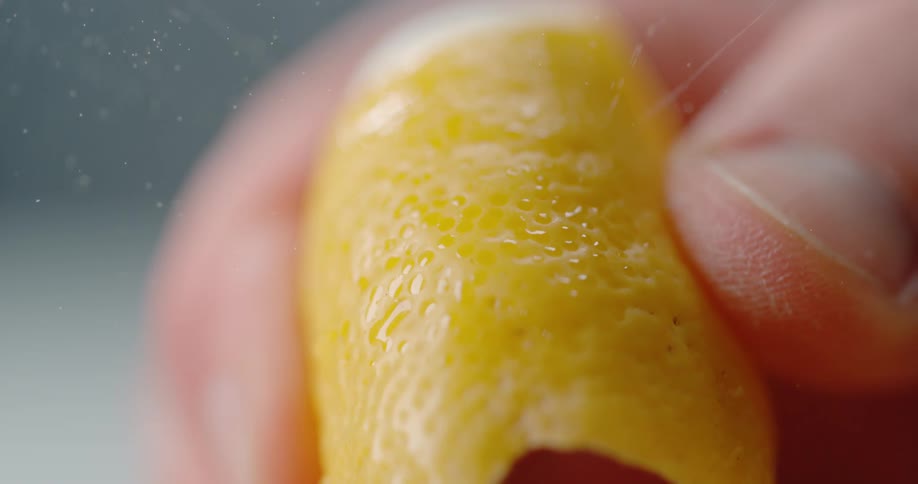 A person in a room squeezing an orange peel with their hand